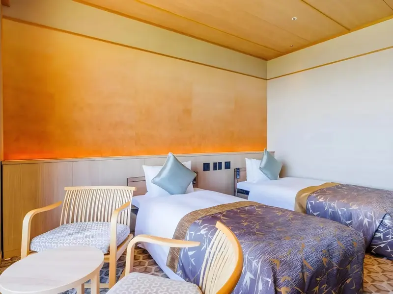 Une chambre lumineuse avec deux lits simples et des fauteuils.