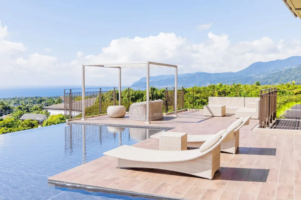 Terrasse avec piscine à débordement et vue sur la mer et les montagnes.