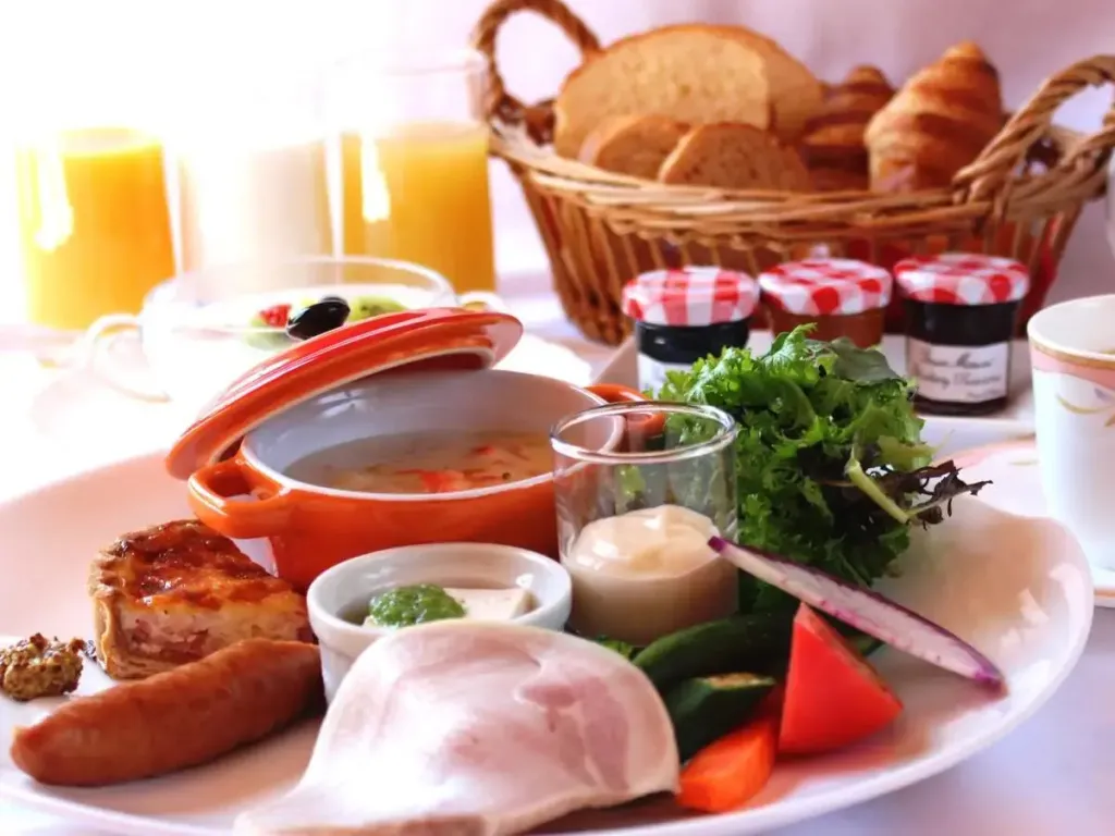 Un copieux petit-déjeuner est présenté sur une table avec des viennoiseries, des fruits et des plats chauds.