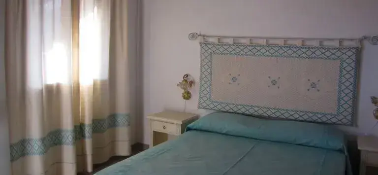 Une chambre lumineuse avec un lit recouvert d'une couverture turquoise et une tête de lit décorative.