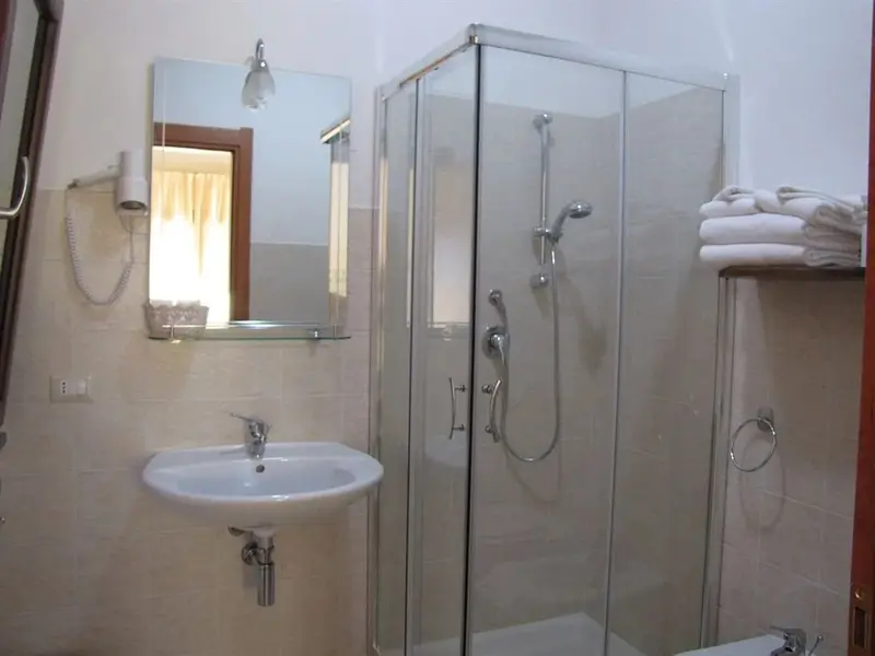 Une salle de bain claire avec douche vitrée et lavabo.