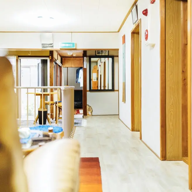 Un couloir intérieur mène à un espace lumineux avec des tables et des chaises.
