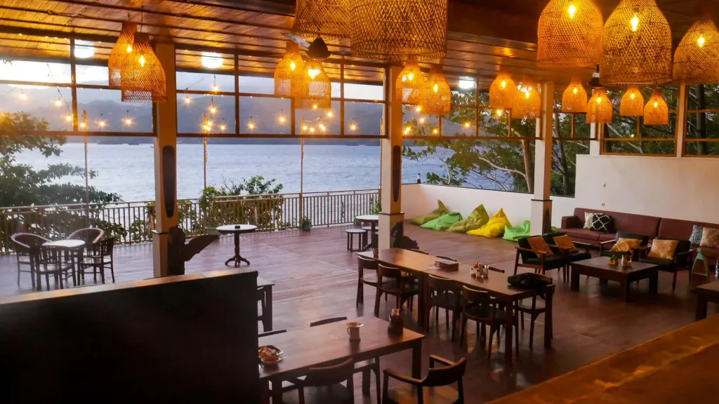 Une salle à manger ouverte sur une vue de mer au coucher du soleil.