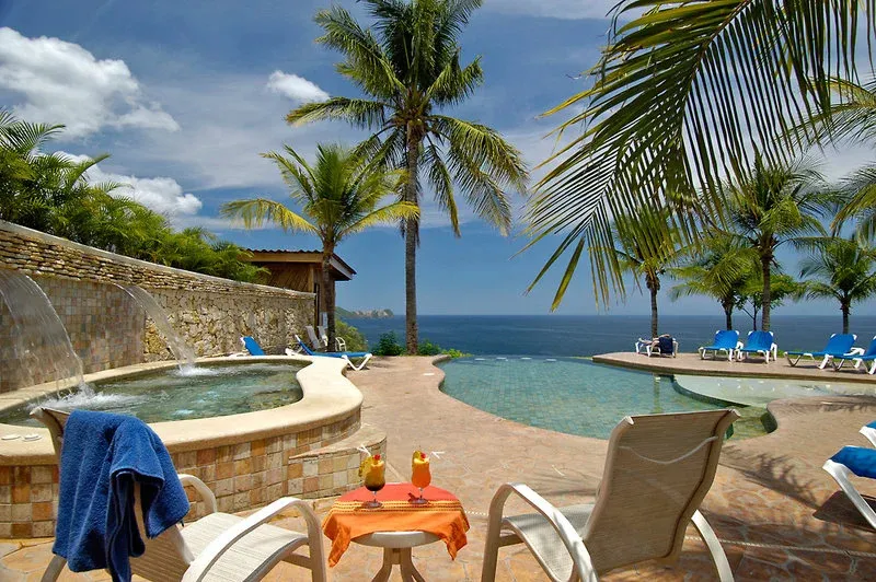 Transats et jacuzzi au bord d'une piscine avec vue sur la mer.