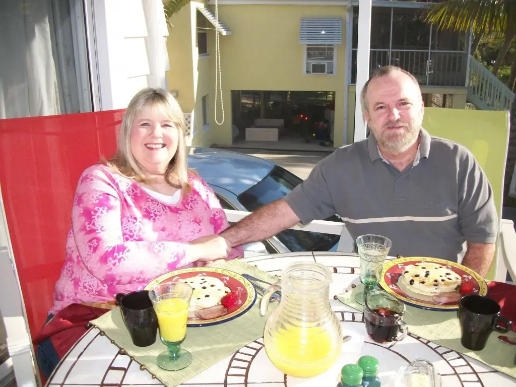Un couple souriant est assis à une table pour prendre un petit-déjeuner ensoleillé.