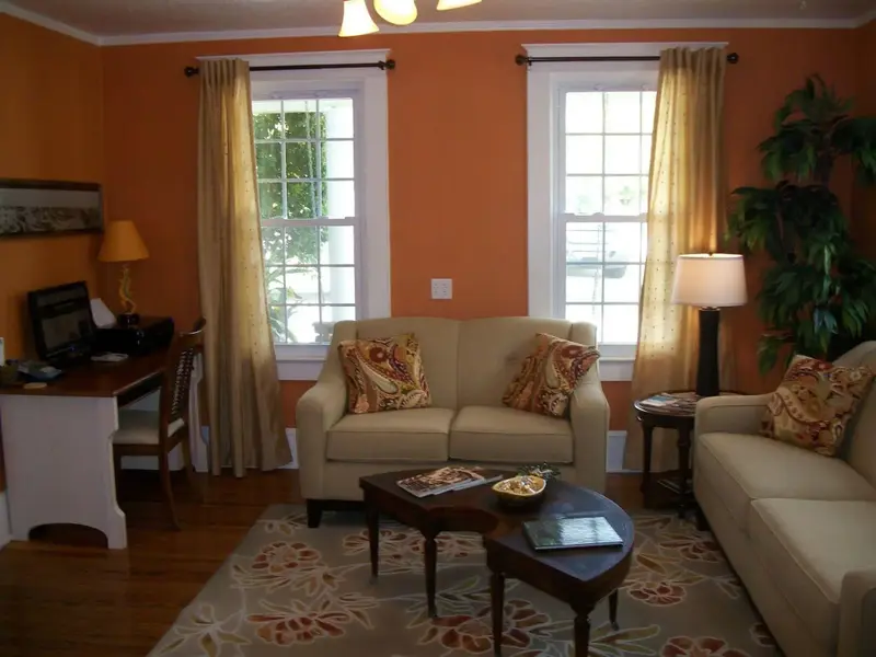 Un salon chaleureux avec deux canapés et un bureau près des fenêtres.