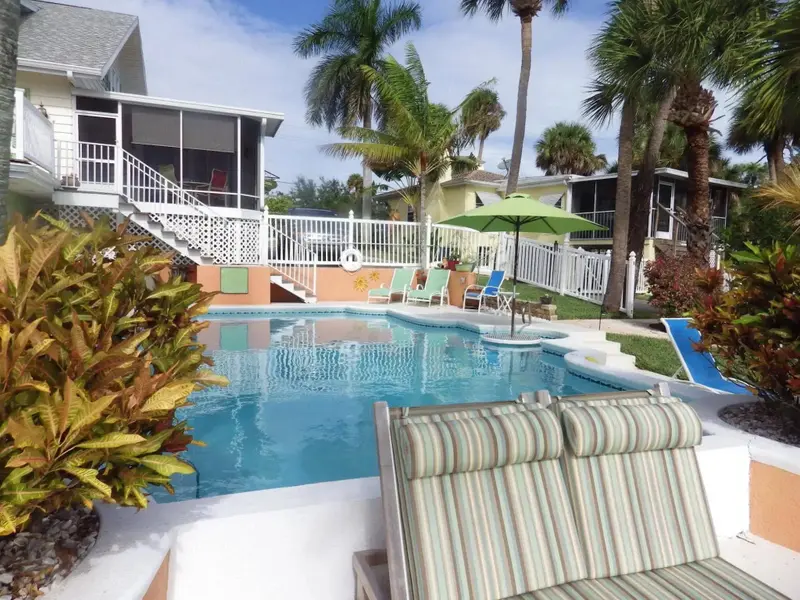 Une piscine bordée de chaises longues et de végétation tropicale.
