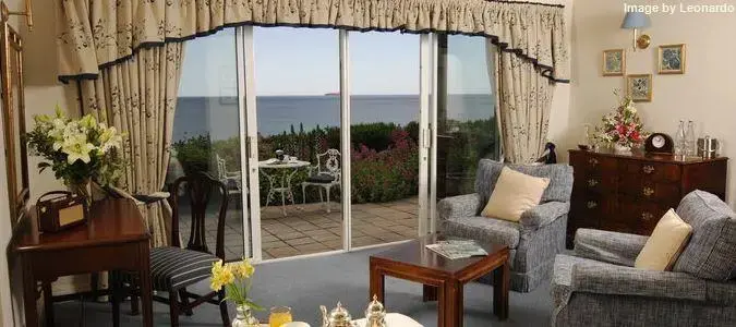 Un salon lumineux s'ouvre sur une terrasse fleurie avec vue sur la mer.