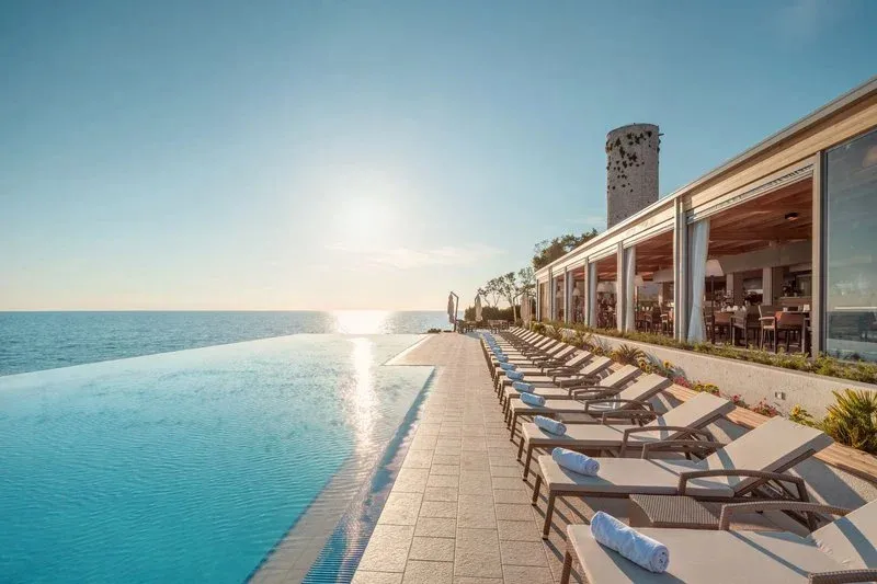 Transats alignés au bord d'une piscine à débordement avec vue sur la mer.