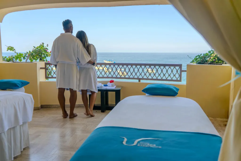 Un couple se tient sur une terrasse donnant sur la mer.
