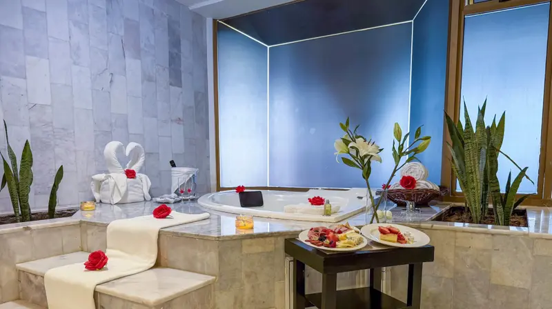 Bain à remous décoré de fleurs et de serviettes dans une salle de bain lumineuse.