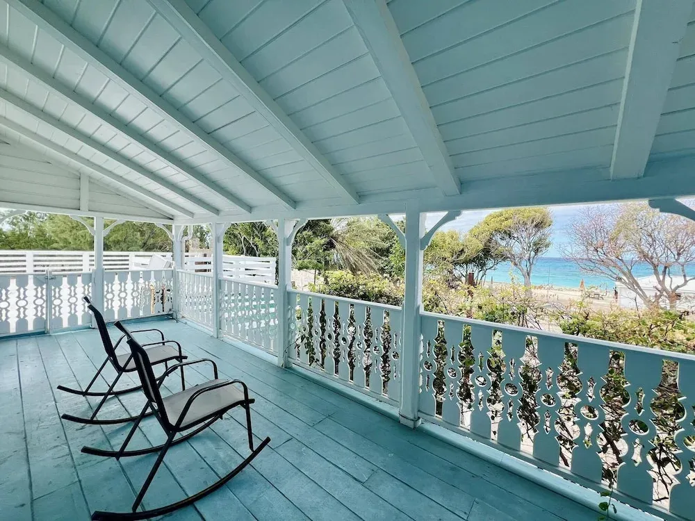 Terrasse couverte avec des fauteuils à bascule donnant sur la mer.