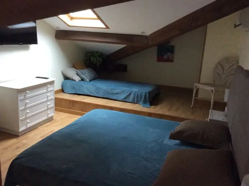 Une chambre mansardée avec deux lits simples et un lit double.