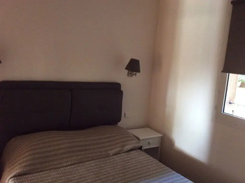 Une chambre lumineuse avec un lit et une table de chevet.