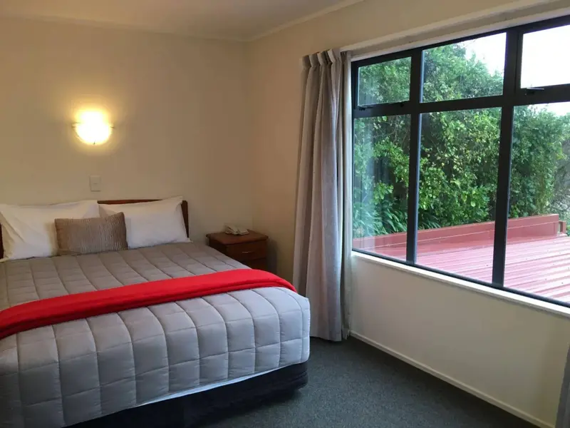 Une chambre lumineuse avec un grand lit et une vue sur la végétation.