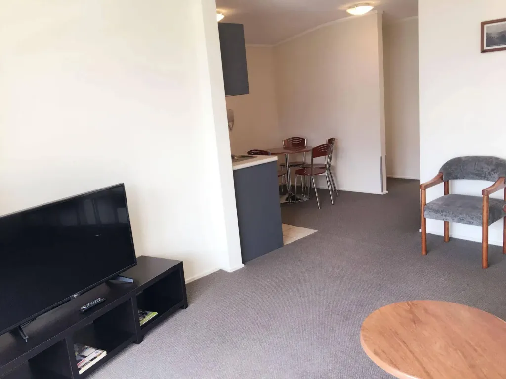Un salon lumineux avec un téléviseur et un coin repas attenant.