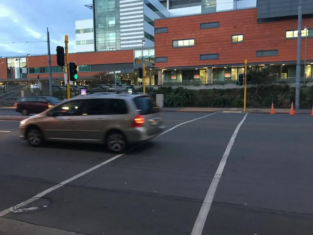 Une voiture circule sur une route en ville près de bâtiments modernes.