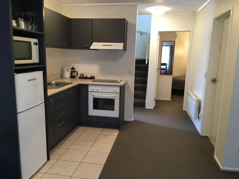 Une cuisine équipée s'ouvre sur un couloir menant à une autre pièce.
