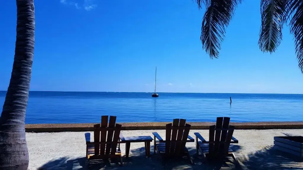 Des fauteuils en bois sont disposés sur une plage de sable fin face à la mer.