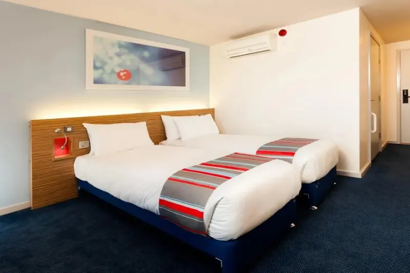 Une chambre moderne avec deux lits simples et un tableau au mur.