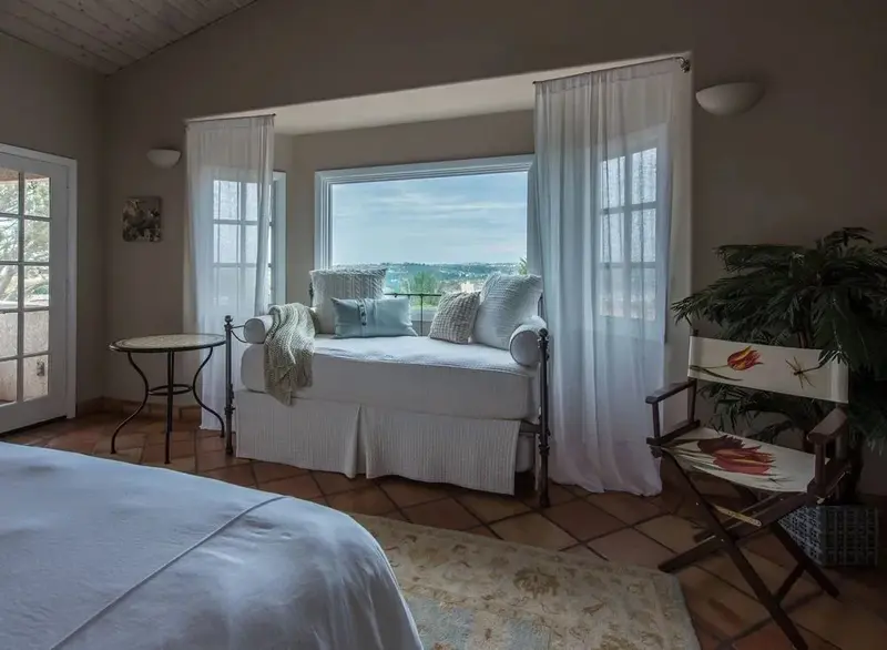 Une chambre lumineuse avec un coin lecture près d'une fenêtre.