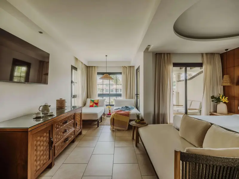 Espace de vie lumineux avec canapé, télévision et accès à une terrasse.