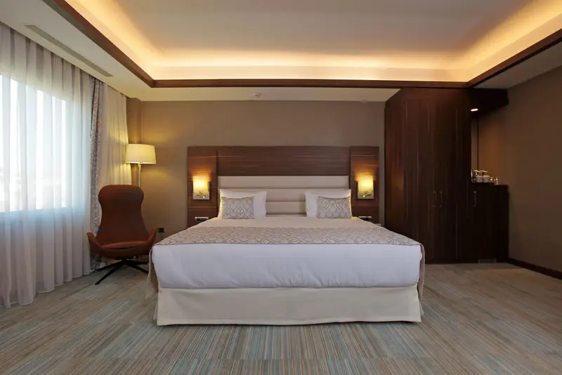 Une chambre lumineuse avec un grand lit et un fauteuil.