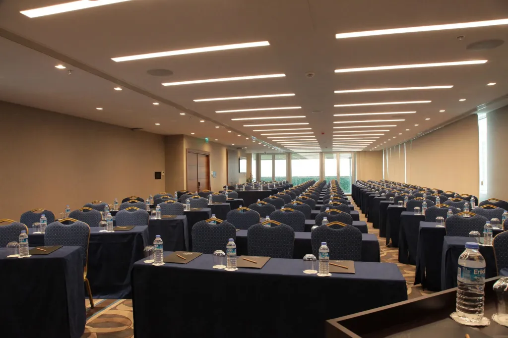Une grande salle de réunion avec de nombreuses tables alignées et des chaises.
