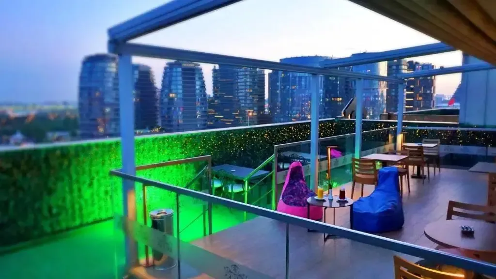Terrasse aménagée avec mobilier de détente et vue sur une ville illuminée.