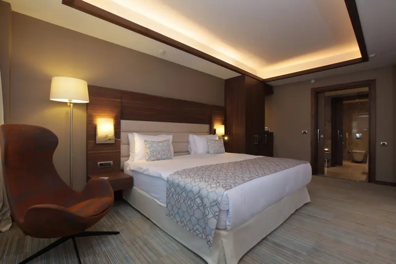 Une chambre lumineuse avec un grand lit et un fauteuil.