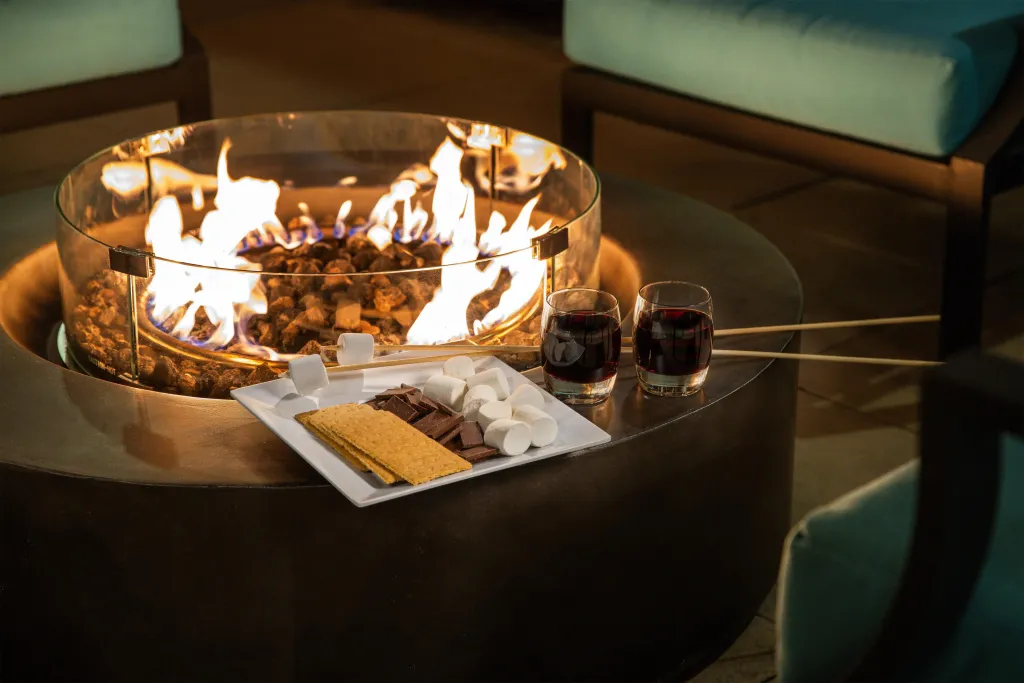 Un feu de cheminée extérieur avec des verres de vin et des marshmallows.