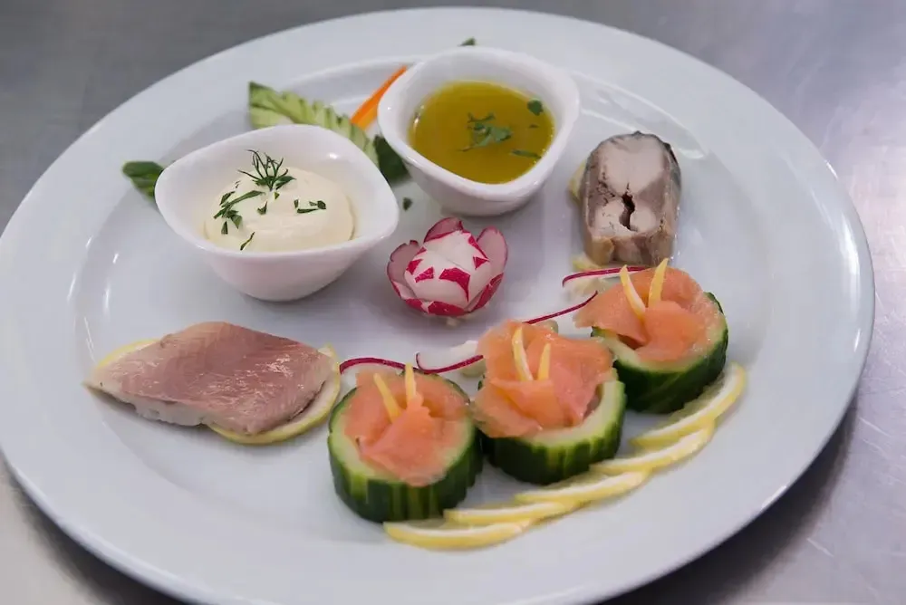 Assiette de hors-d'œuvre variés avec poisson, légumes et sauces.