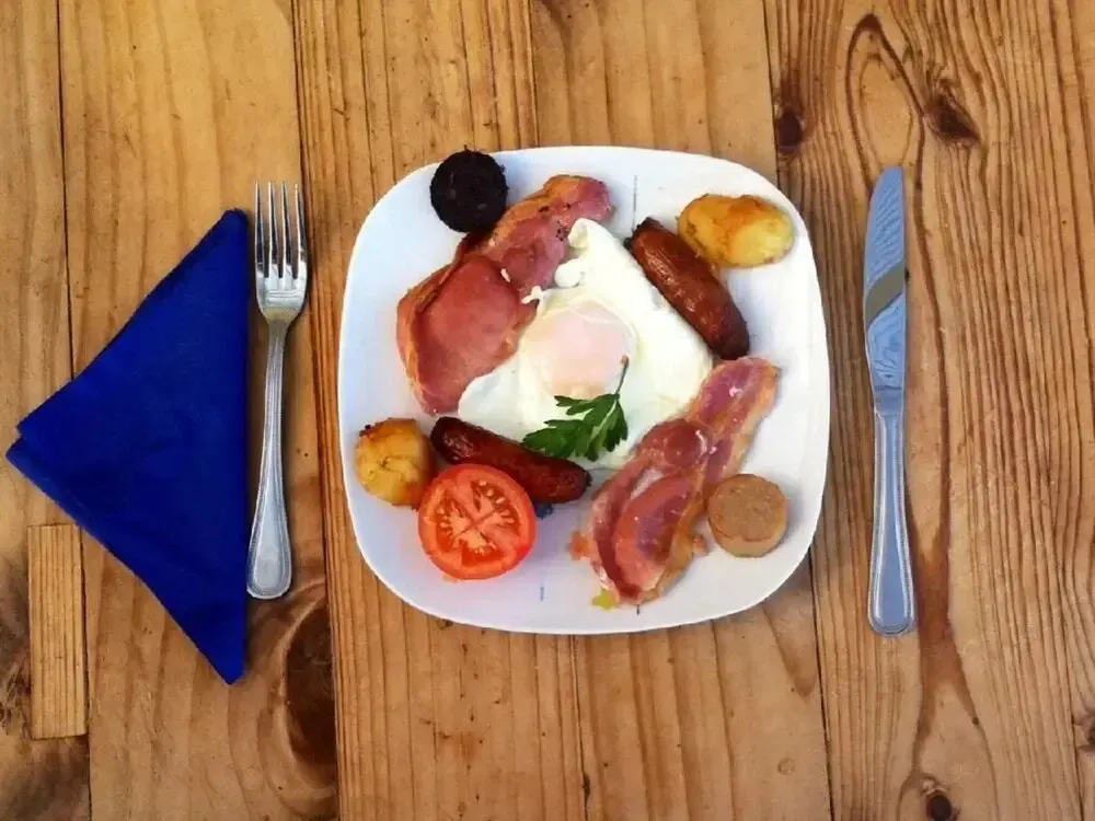 Assiette copieuse avec oeuf au plat, bacon, saucisse et accompagnements.