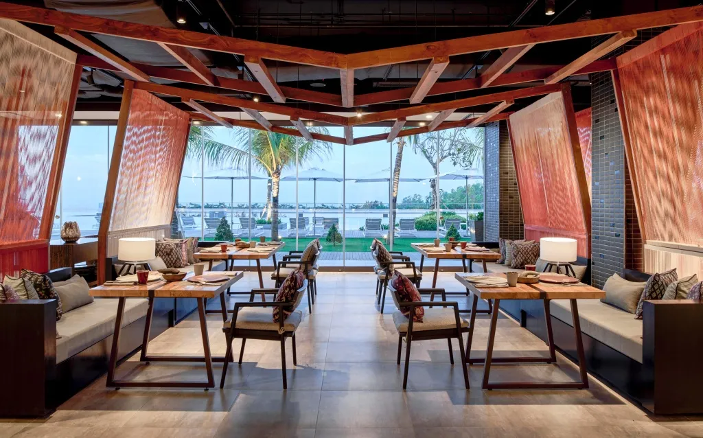 Une salle à manger lumineuse offre une vue sur la mer et la végétation.