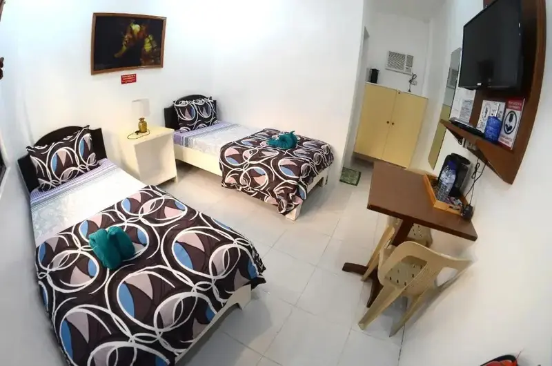Une chambre lumineuse avec trois lits simples et un espace détente.