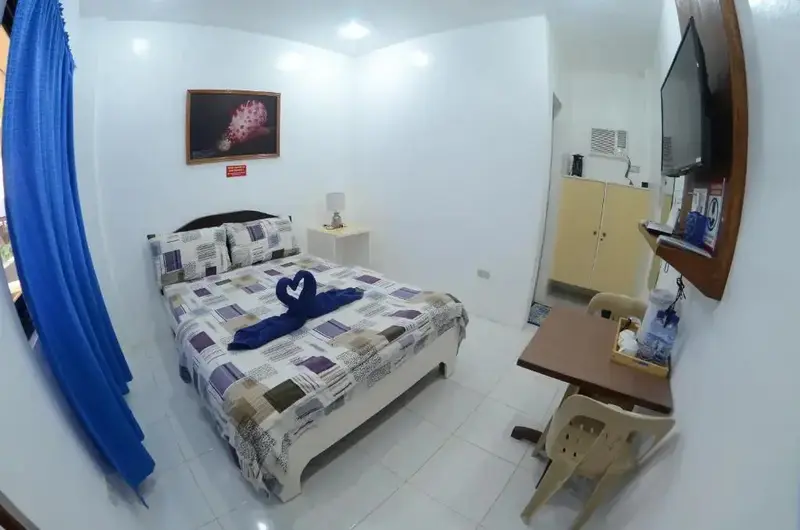 Une chambre lumineuse avec un lit double et un coin repas.