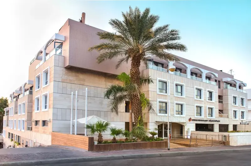 Façade d'un bâtiment moderne avec des palmiers devant.