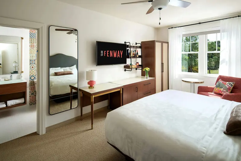 Une chambre lumineuse avec un grand lit et un bureau en bois.