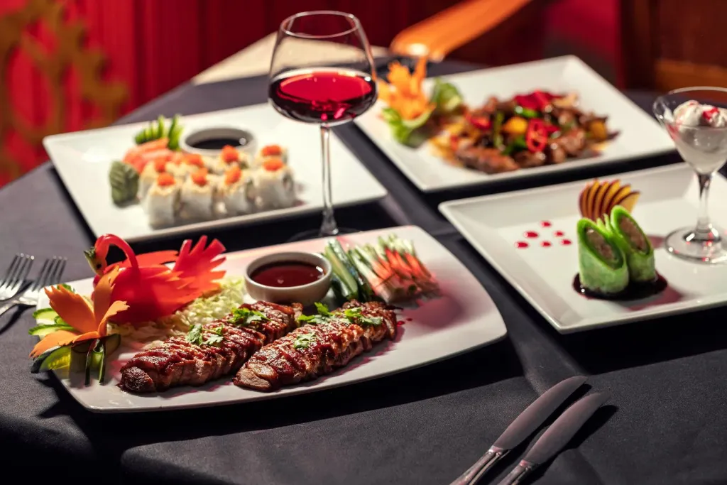 Une table est dressée avec plusieurs plats raffinés et des verres de vin.