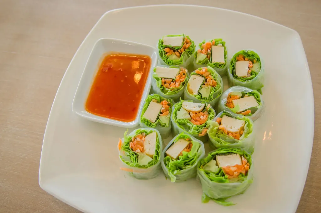 Assiette de rouleaux de printemps frais accompagnés d'une sauce.