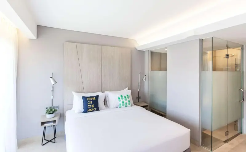 Une chambre lumineuse avec un grand lit et une douche à l'italienne.
