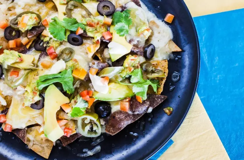 Assiette de nachos garnis d'ingrédients frais et colorés.
