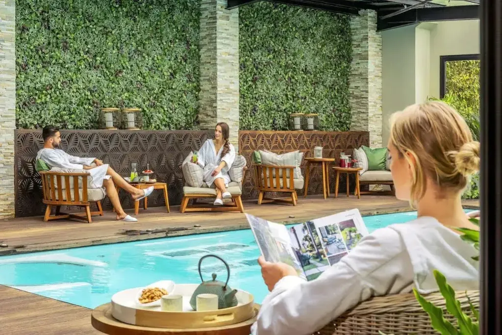 Des personnes se détendent près d'une piscine dans un espace extérieur aménagé.
