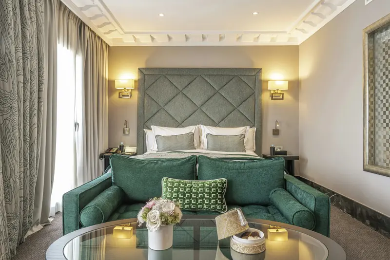 Une chambre lumineuse avec un grand lit et un canapé vert.
