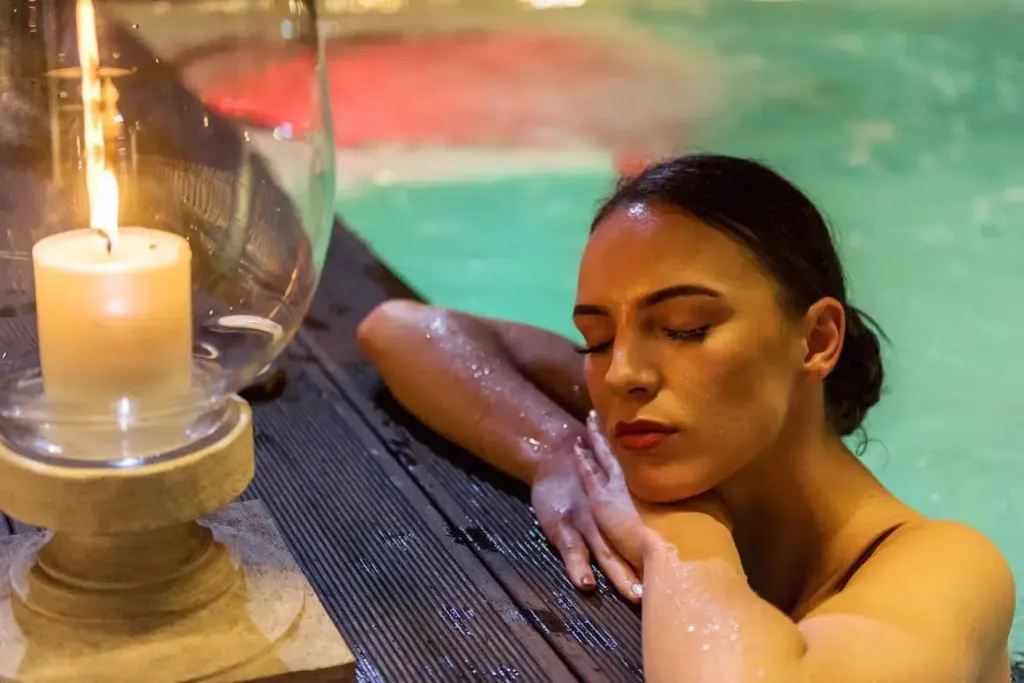 Une femme se détend dans une piscine éclairée par une bougie.