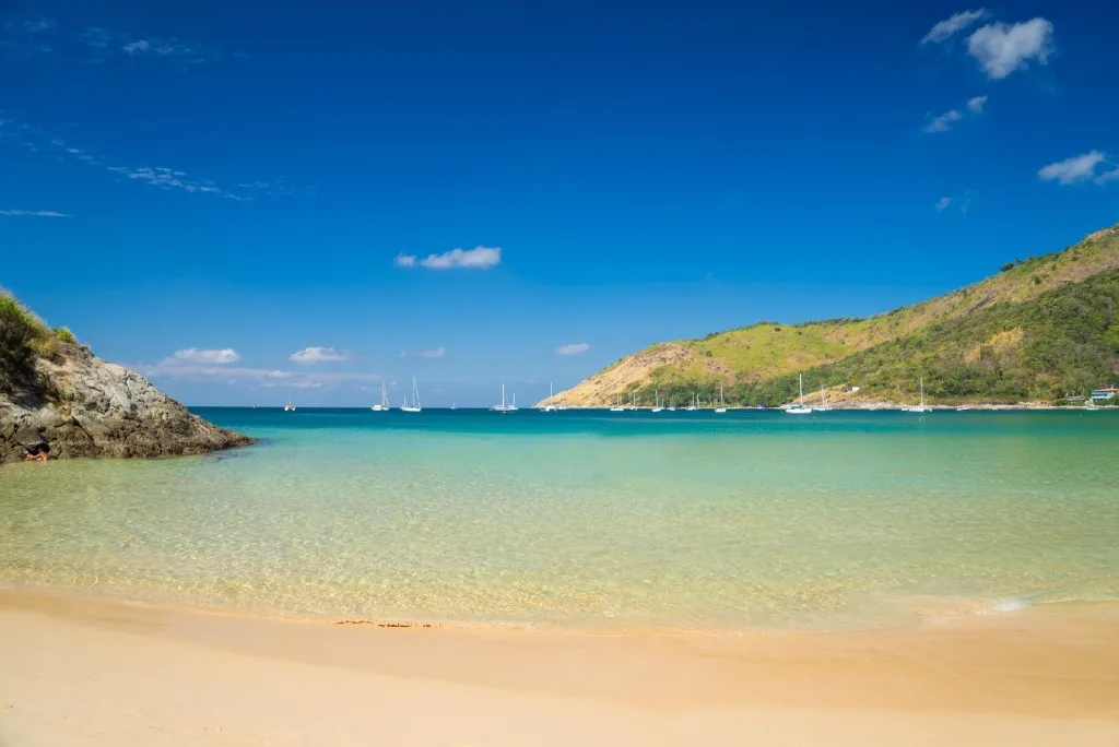 Une plage de sable fin borde une eau turquoise et calme.
