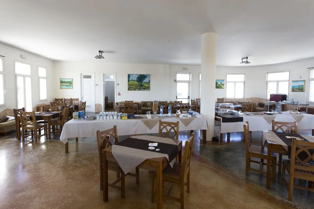 Une salle lumineuse est aménagée avec des tables et des chaises pour les repas.