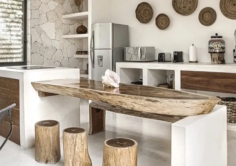 Une cuisine moderne avec un îlot central en bois brut et des tabourets en tronc d'arbre.