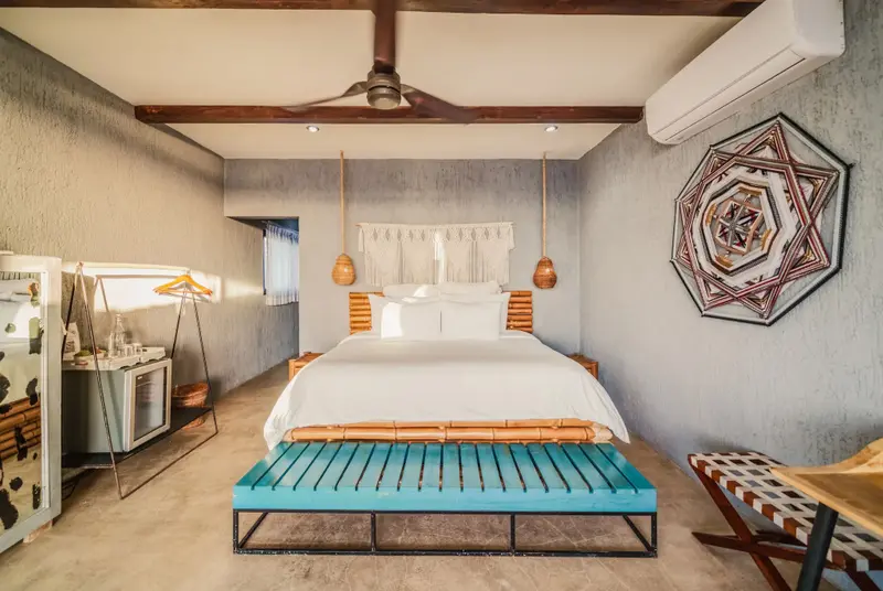 Une chambre lumineuse avec un grand lit recouvert de blanc.