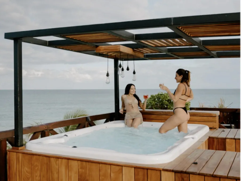Deux femmes se détendent dans un jacuzzi extérieur avec vue sur la mer.